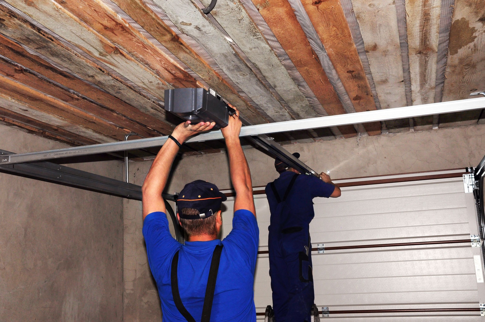 Contractors installing garage door opener. Repair garage door opener system.